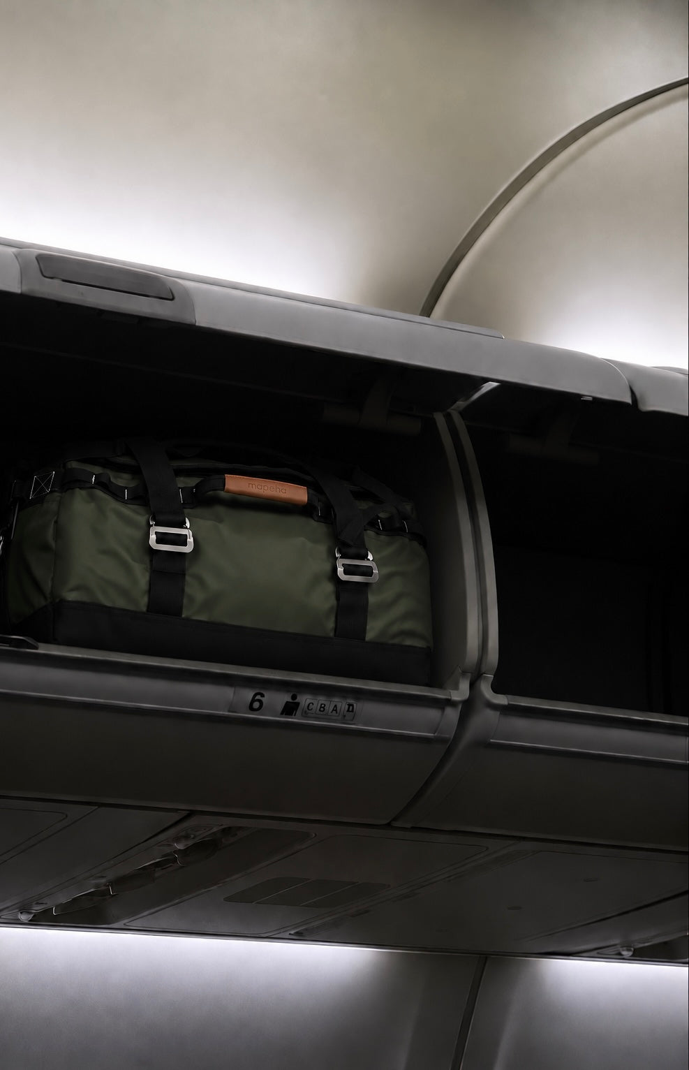 Bolsa de viaje Mapeha colocada en un compartimento superior de avión